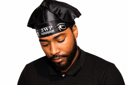A man wearing a black satin-like beret-style hat with a black headband featuring white '3WP' lettering and a stylized 'Wave' logo, paired with a black ribbed polo shirt, against a plain white background.